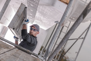 Scaffolding Installation by Caucasian Construction Worker in His 30s. Industrial Theme.