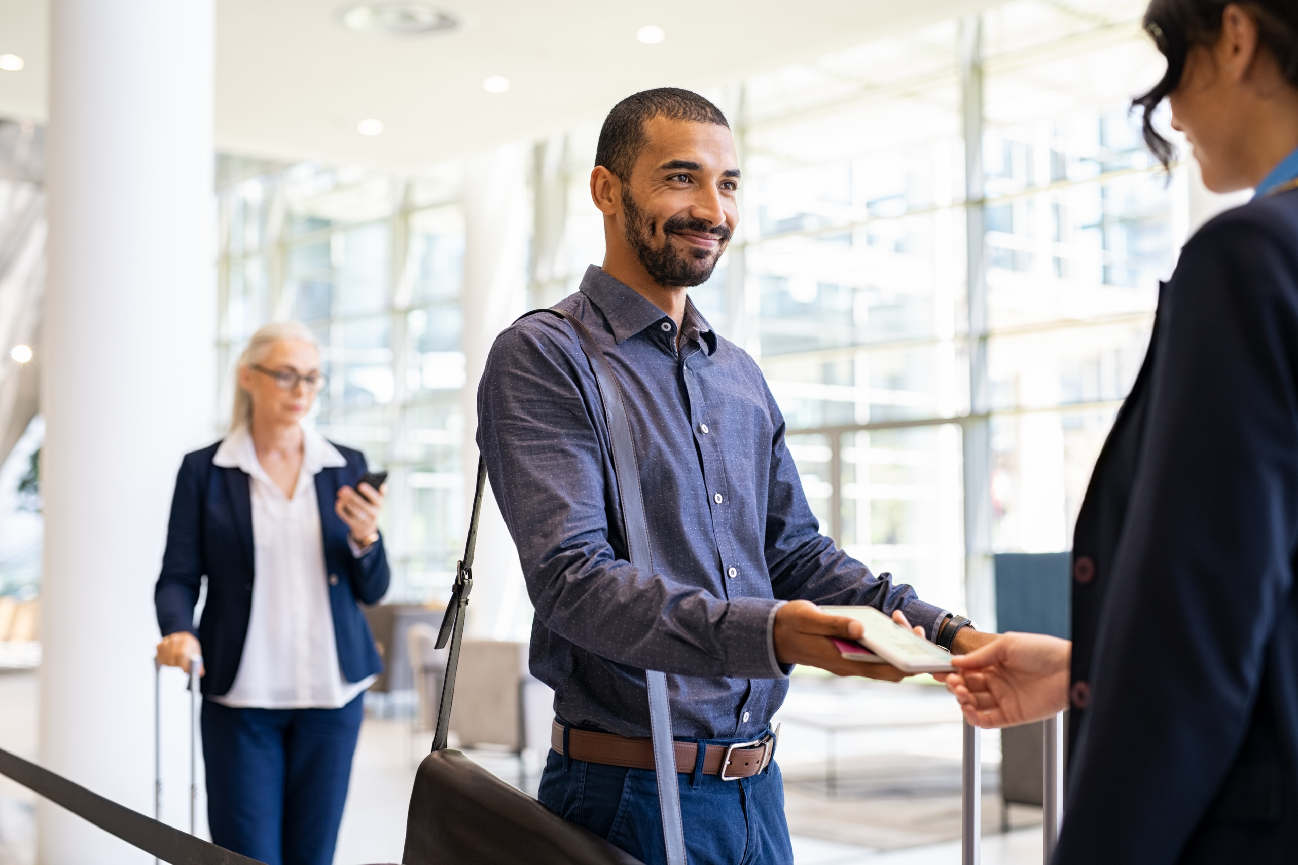 Indian passenger showing e-ticket to flight attendant at boarding gate. Young middle eastern businessman showing boarding pass on mobile phone to air hostess. Smiling multiethnic business man showing eticket to attendant at airport.