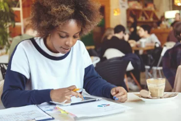 young woman with curly hair using tablet cafe 1